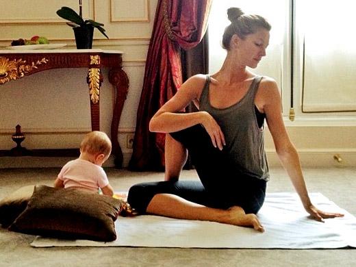 Modelo Gisele Bündchen pratica yoga enquanto sua filha brinca